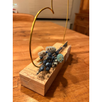 hartje in goudkleurige metaaldraad met droogbloemen in blauw- of rozetinten op steigerhouten plankje