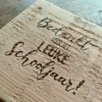 Tekst einde schooljaar in pyrografie op hout