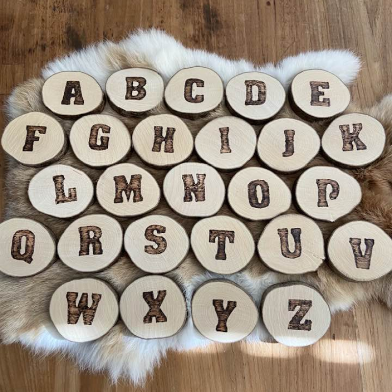 Letter in pyrografie op boomschijfje