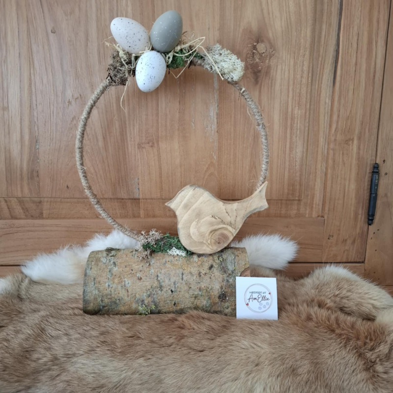 vogel uit gewaxt grenenhout tegen een met jutetouw omwonden ring gedecoreerd met led-lichtjes op een stronk van natuurhout